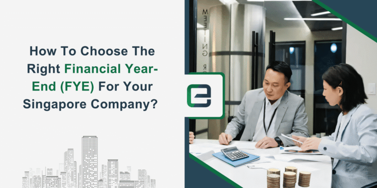 Two business professionals discussing financial reports at a modern office desk with coins, calculator, and documents. Visual banner promoting guidance on selecting the right Financial Year-End (FYE) for Singapore companies.