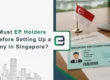 Singapore Employment Pass (EP) card on desk with documents and Singapore flag